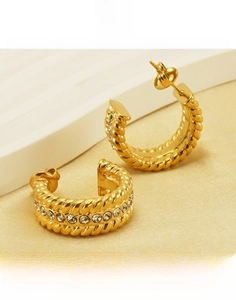 Close-up of gold titanium steel hoop earrings with twisted texture and crystal inlay