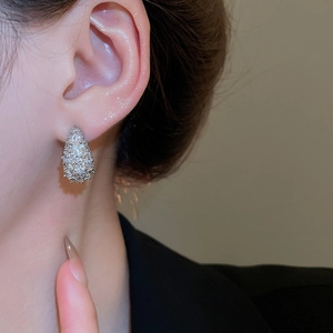 Close-up of sparkling silver drop earrings with cubic zirconia worn on a female ear
