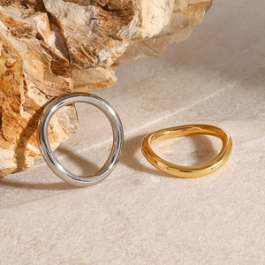 Polished stainless steel rings in silver and gold on a minimalist stone background