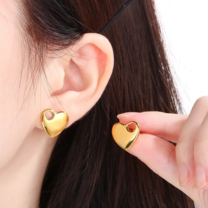 Detailed view of gold-plated 18K stainless steel heart-shaped stud earrings on model