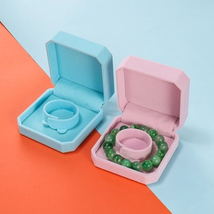 Detail of octagonal velvet bracelet boxes in sky blue and pink with ring holders