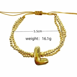 Vue détaillée d'un bracelet de perles dorées avec un pendentif lettre L initiale brillant