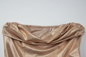 Vue détaillée du décolleté drapé et de la texture du tissu métallique doré brillant