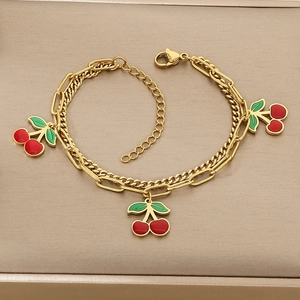 Detail of gold double-layered bracelet with red cherry pendants and lobster clasp