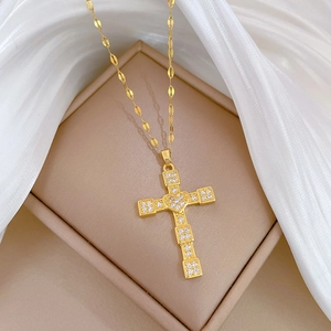 Detailed view of a gold cross pendant with a central heart and crystals on silk