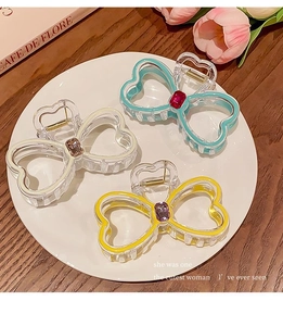 Detailed top view of rhinestone bow hair claws in three colors on a ceramic plate