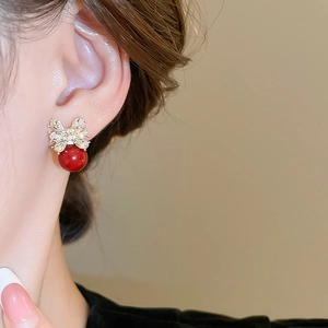 Detailansicht der Schleifen-Ohrstecker mit glänzenden Kristallen und roter Perle