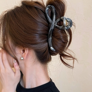 Macro detail of a large marble patterned hair claw clip styled on a woman's hair