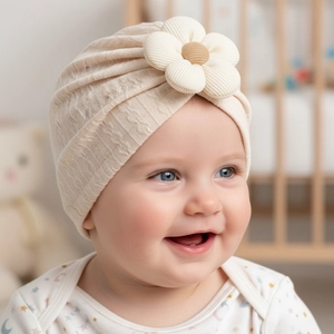 Detail of baby turban hat featuring a beige knit flower and soft textured fabric