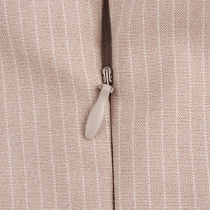Detail of invisible zipper and striped fabric texture on beige pleated dress