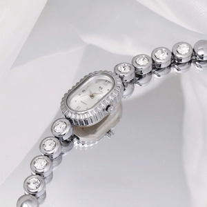 Macro detail of oval dial watch with roman numerals and crystal-encrusted metal strap