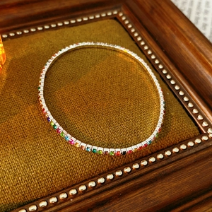 Dettaglio ravvicinato di un bracciale elastico argento con zirconi arcobaleno su velluto