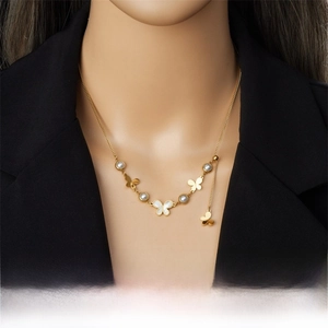 Detail of gold butterfly pendant necklace with pearls on a model in a black suit