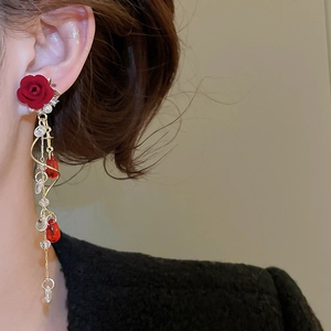 Nahaufnahme eleganter langer Quastenohrringe mit roten beflockten Rosen und Perlen an Modell