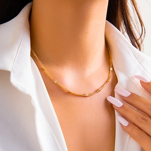 Detail of multi-layered gold woven chain necklace featuring textured metal blocks