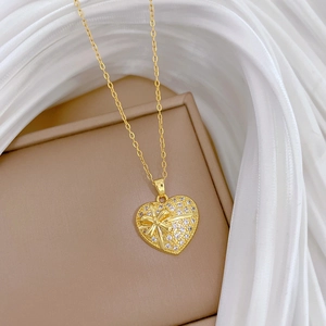 Collier cœur en titane doré de luxe avec pendentif nœud en cristal sur tissu blanc