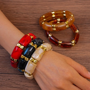 Detailed view of stacked acrylic bangles in marble textures with gold metal spacers
