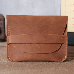 Detail of brown crazy horse leather card holder with handmade stitching on wood surface