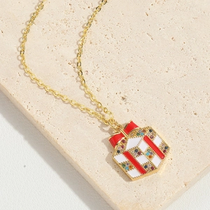 Detail shot of a festive gift box pendant necklace with enamel and small gems on stone
