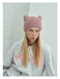 Detail shot of a knit cat ear hat in rose pink with delicate bow tie decorations