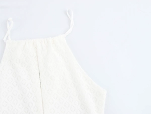 Detail of white halter neck dress featuring textured hollow-out geometric knit fabric