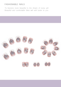 Detail of pink gradient press-on nails with white heart patterns and small rhinestones