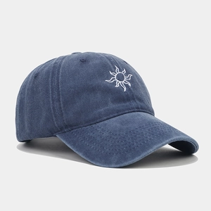 Close-up of white sun embroidery on washed navy cotton baseball cap with curved brim