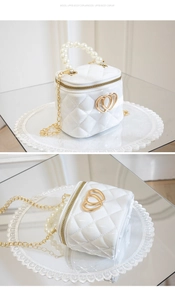 Detail of white quilted mini jelly bag with pearl handle and golden heart clasp