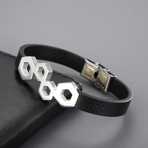 Macro detail of stainless steel clasp and woven leather bracelet with hex patterns
