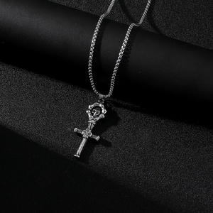 Détail du pendentif croix en acier inoxydable argenté avec crâne et finition texturée