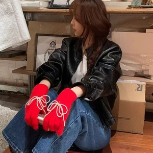 Detail of red knitted gloves with elegant imitation pearl bow decoration for women