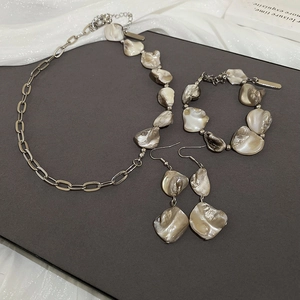 Dettaglio di ciondoli a conchiglia su set di collana e bracciale a catena dorata elegante