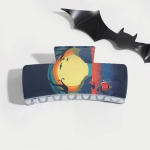 Detail of Halloween hair claw clip featuring moon, bats, and pumpkin on dark blue resin