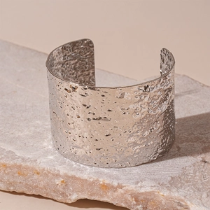 Detail of silver hammered texture cuff bracelet on a natural stone background
