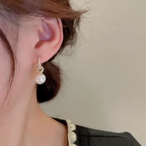 Vue détaillée d'une boucle d'oreille perle avec fermoir doré serti de zircons sur l'oreille