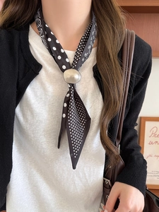 Detail of silver oval scarf buckle with paisley pattern silk necklace on a model
