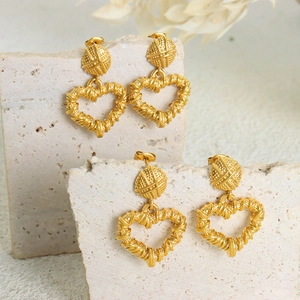 Vintage gold heart pendant earrings with twisted rope texture on stone backdrop
