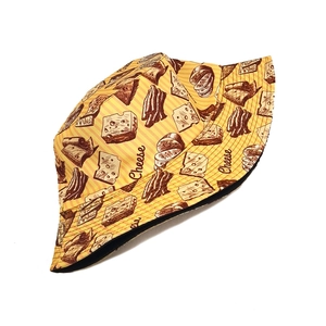 Dettaglio cappello alla pescatora giallo con stampe di formaggio e fodera nera