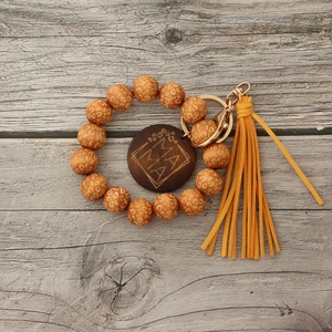 Detail of leopard print wooden beads keychain featuring yellow tassel and MAMA engraving