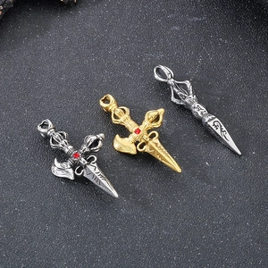 Macro detail of three steel vajra pendants with red gemstones on black background