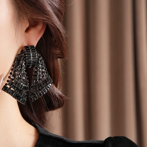 Close-up of model wearing black rhinestone bow earrings with tiered fringe detailing