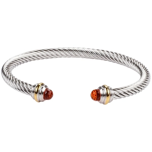 Detailed close-up of silver twisted cable bracelet with gold accents and orange gemstones