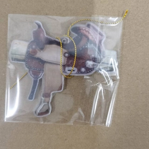 Detail of western saddle keychain pendant in protective packaging with golden cord