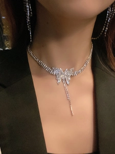 Silver butterfly pendant necklace with rhinestone tassels worn on a black blazer