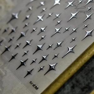 Macro shot of silver 3D four-pointed star nail stickers with metallic reflective finish