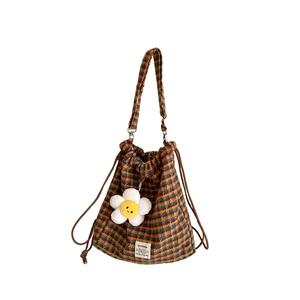 Checkered wool drawstring backpack with floral charm and adjustable strap on white background