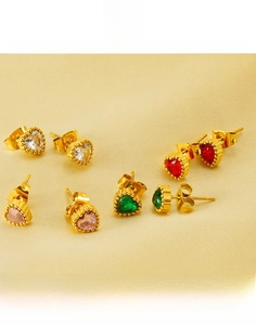 Macro detail of colorful heart-cut zircons set in polished gold titanium steel earrings