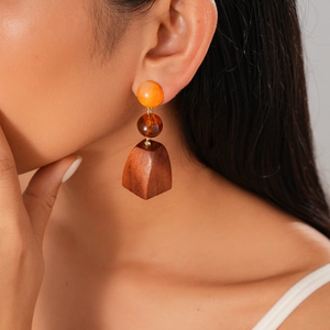 Close-up of model wearing boho wooden earrings with amber resin beads and geometric pendant