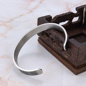 Détail d'un bracelet manchette viking argenté avec motifs celtiques sur bois ancien