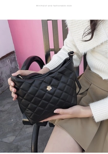 Close-up of black quilted bucket bag with rose gold floral metallic buckle for women